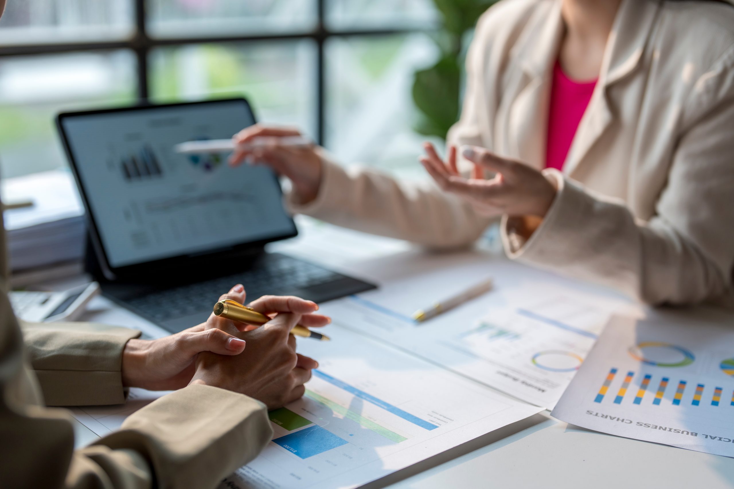 Two,Businesswomen,Are,Discussing,Financial,Data,Displayed,On,A,Digital
