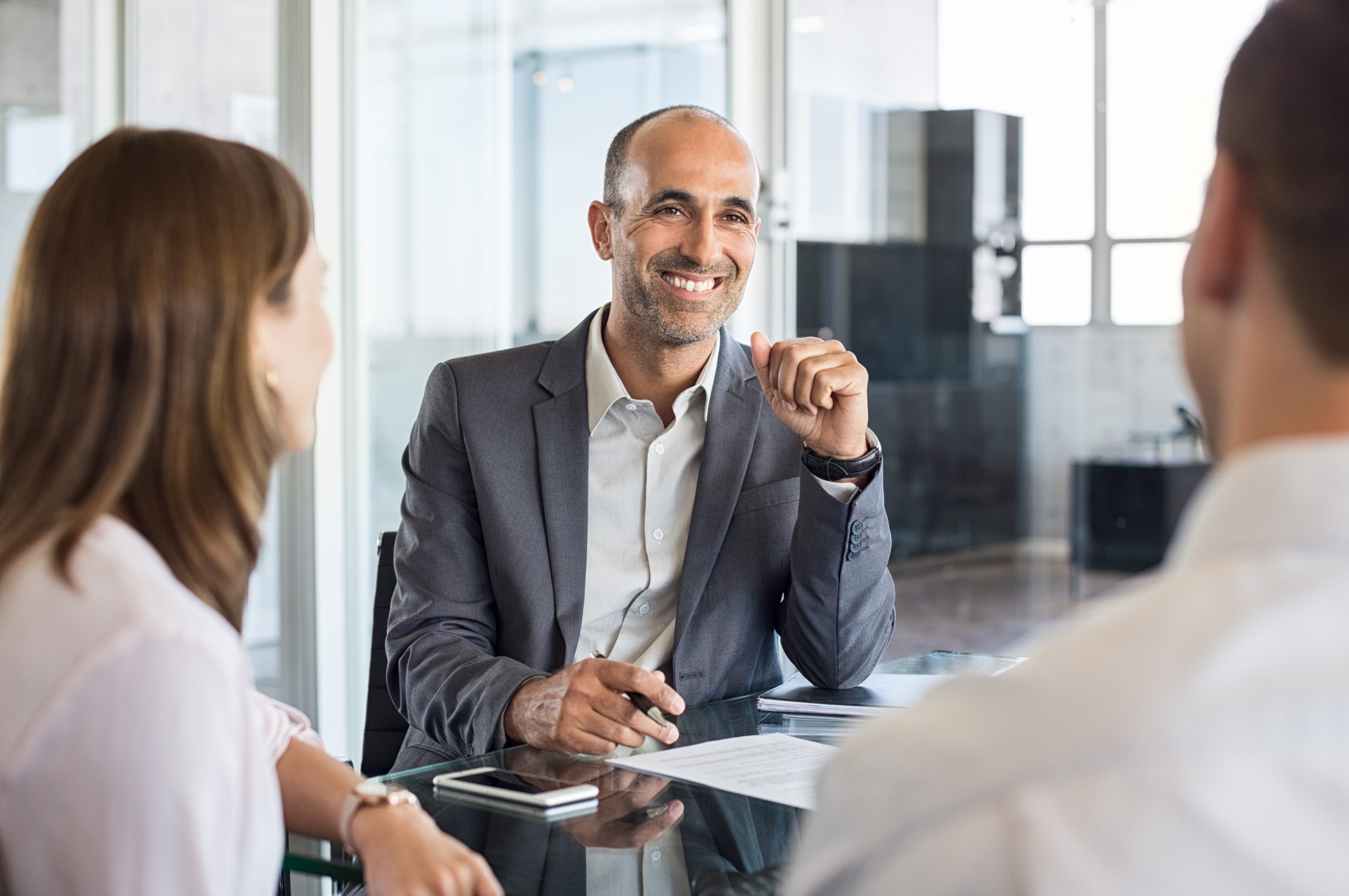 Mature,Financial,Agent,In,Meeting,Sitting,With,Young,Couple.,Happy